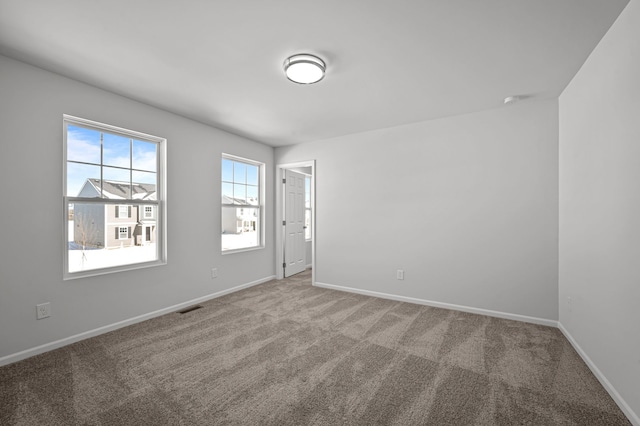 carpeted spare room featuring baseboards and visible vents