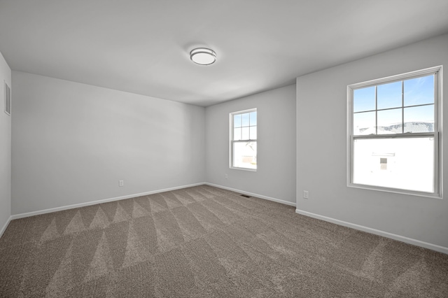 spare room featuring visible vents, baseboards, and carpet flooring