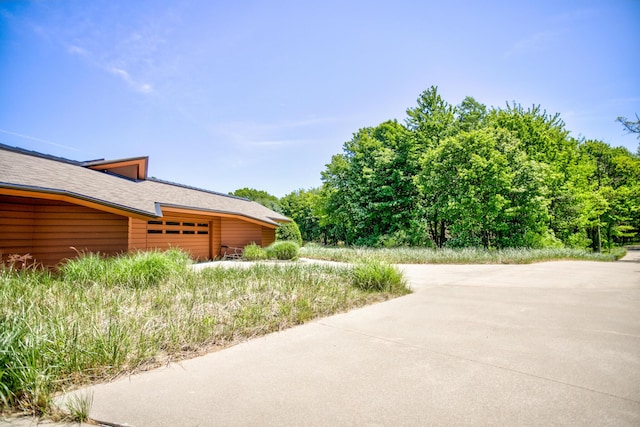 view of side of home with a garage and roof with shingles