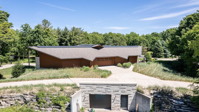 view of front of home featuring a garage, stone siding, metal roof, a standing seam roof, and roof mounted solar panels