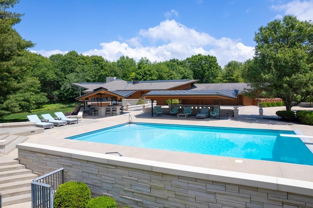 pool with outdoor lounge area, a patio area, outdoor dry bar, and a diving board