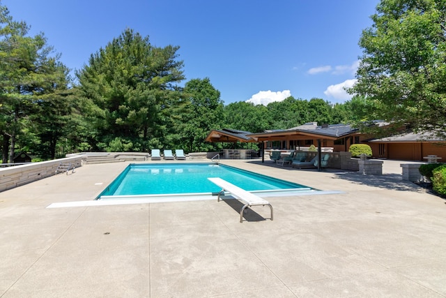 pool featuring a diving board and a patio