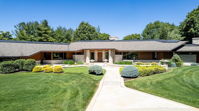 view of front of property featuring a chimney, a front lawn, and solar panels