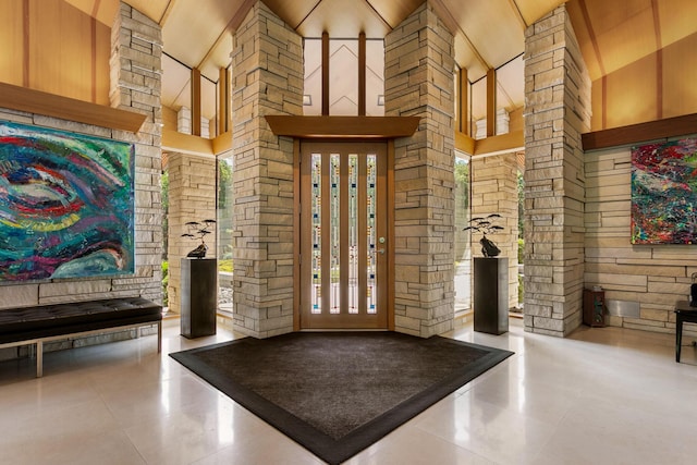 entrance foyer featuring tile patterned flooring, a towering ceiling, and ornate columns