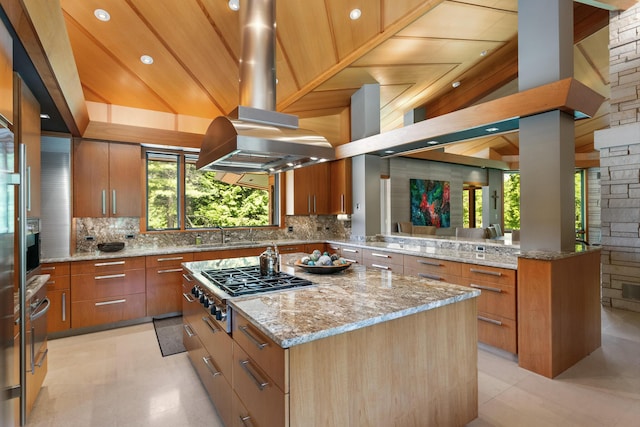 kitchen featuring island range hood, stainless steel gas cooktop, a sink, a center island, and decorative backsplash