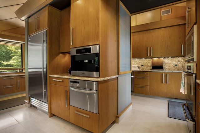 kitchen with built in appliances, tasteful backsplash, visible vents, and brown cabinets