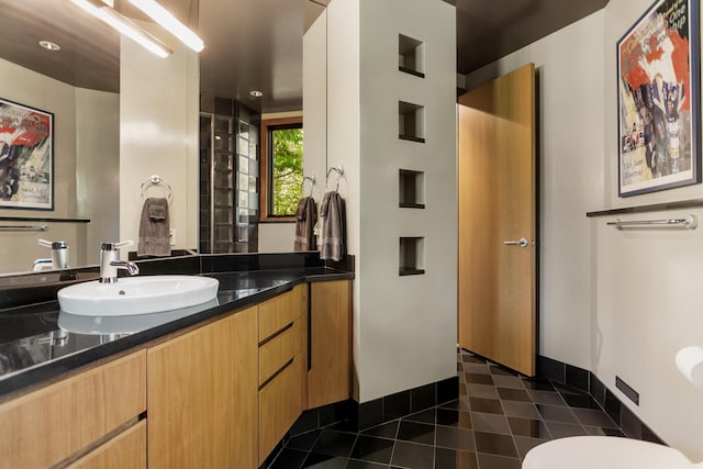 bathroom with toilet, vanity, baseboards, and tile patterned floors