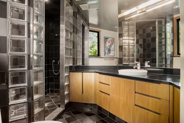 bathroom featuring tile patterned flooring, visible vents, vanity, tile walls, and walk in shower