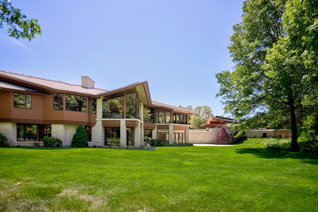 back of house with a sunroom, a yard, and a chimney