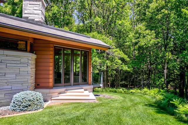 view of exterior entry with a chimney and a lawn