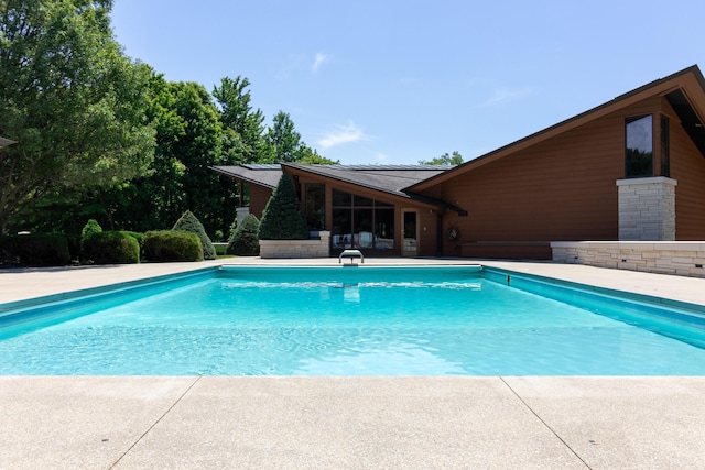 pool with a diving board and a patio