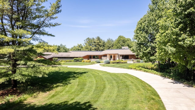 view of front of home with driveway, a front lawn, and a chimney