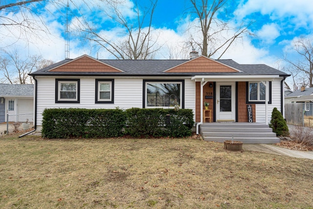 view of front of house featuring a chimney, a shingled roof, a front lawn, and fence