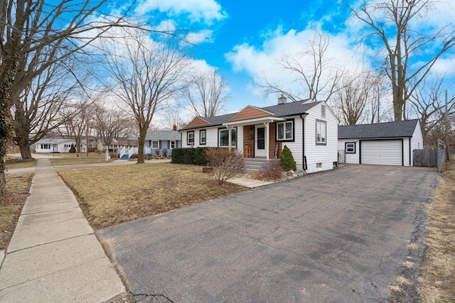 view of front of house with a front lawn, aphalt driveway, a chimney, a garage, and an outbuilding