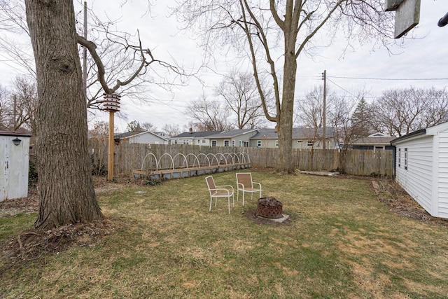 view of yard with an outbuilding, a fenced backyard, and an outdoor fire pit