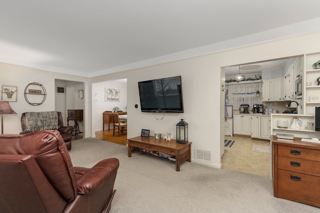 living area featuring visible vents and light carpet