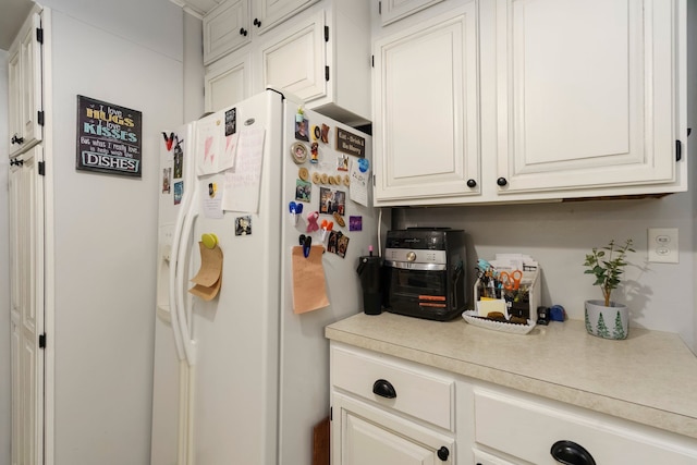 kitchen with white cabinetry, light countertops, and white refrigerator with ice dispenser