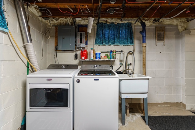 clothes washing area featuring electric panel, a sink, laundry area, and washing machine and clothes dryer