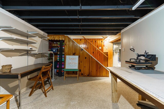 finished basement featuring stairway, light carpet, and wooden walls