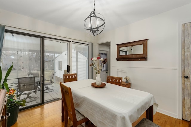 dining area with baseboards, a notable chandelier, and light wood finished floors