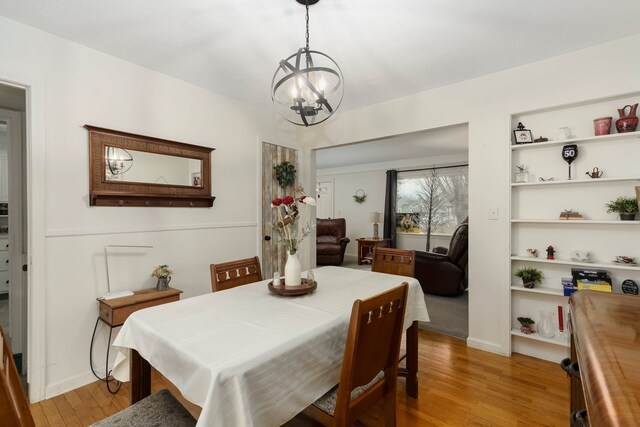 dining area with light wood-type flooring and a chandelier