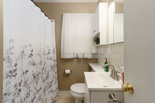 bathroom with tile patterned floors, toilet, backsplash, baseboards, and vanity