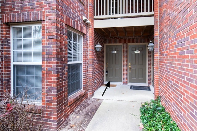 entrance to property featuring brick siding and a balcony