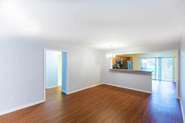 spare room with dark wood-style floors, baseboards, and a chandelier