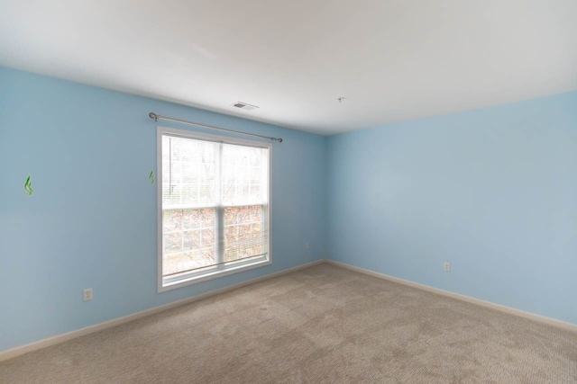 carpeted spare room with visible vents and baseboards