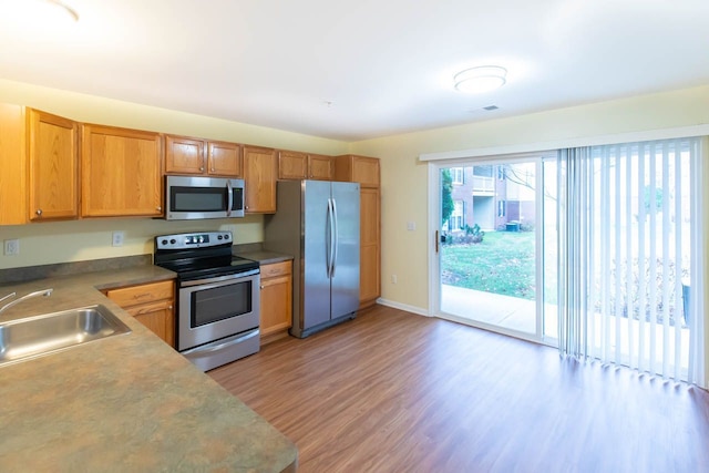 kitchen featuring visible vents, baseboards, light wood finished floors, a sink, and stainless steel appliances