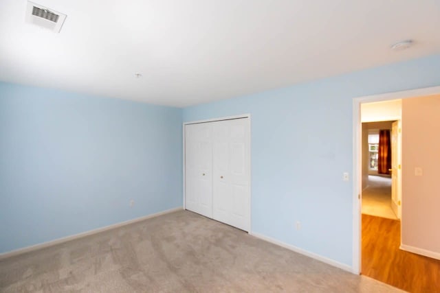 unfurnished bedroom with a closet, visible vents, baseboards, and carpet floors