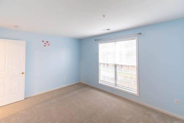 spare room featuring visible vents, carpet, and baseboards