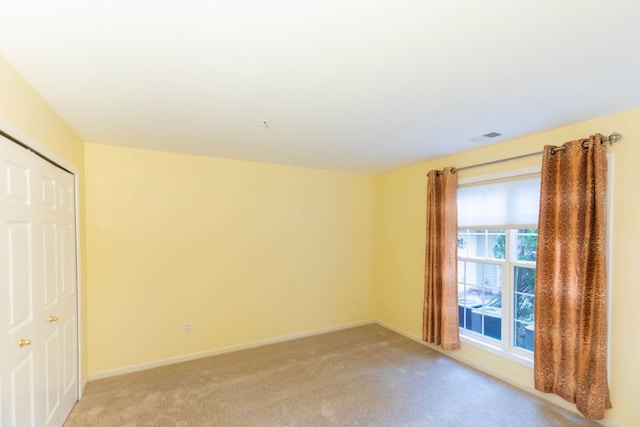 empty room featuring light carpet, visible vents, and baseboards