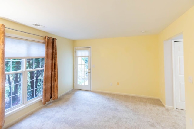 unfurnished room featuring light colored carpet, visible vents, and baseboards