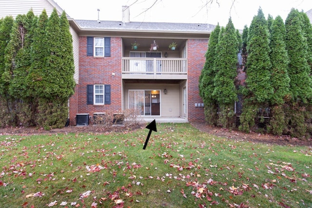 back of property with brick siding, a lawn, cooling unit, and a balcony