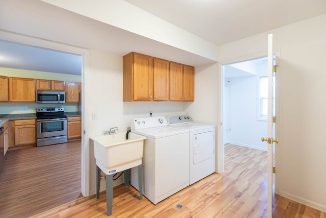 washroom featuring washing machine and dryer, light wood-type flooring, and baseboards