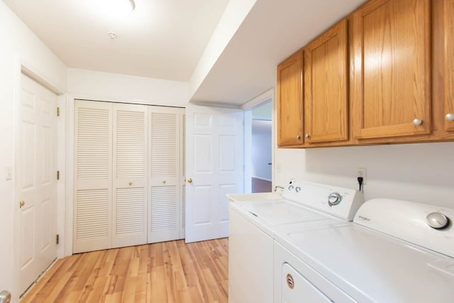 washroom with light wood-type flooring, cabinet space, and washing machine and dryer