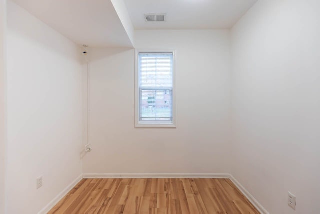 spare room with light wood-type flooring, visible vents, and baseboards