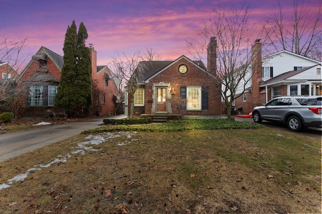 view of front of property featuring brick siding and a lawn