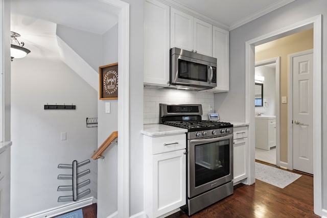 kitchen featuring white cabinets, appliances with stainless steel finishes, ornamental molding, dark wood-style flooring, and backsplash