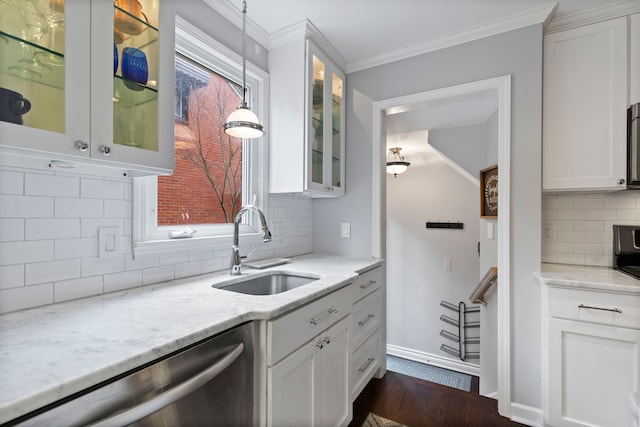 kitchen with white cabinets, light stone counters, ornamental molding, stainless steel dishwasher, and a sink