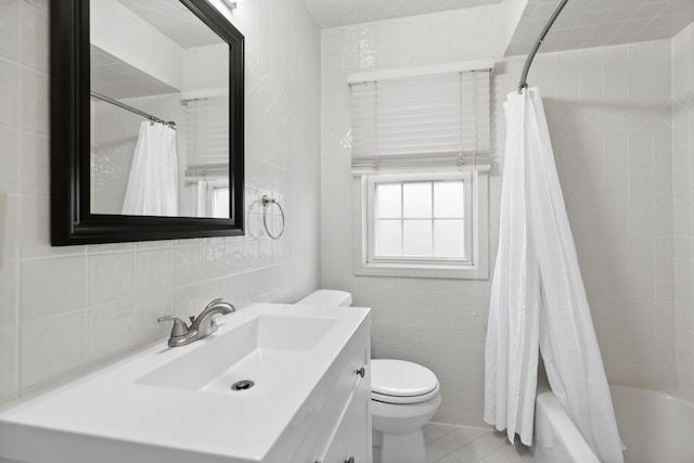 bathroom with toilet, vanity, tile patterned flooring, and tile walls