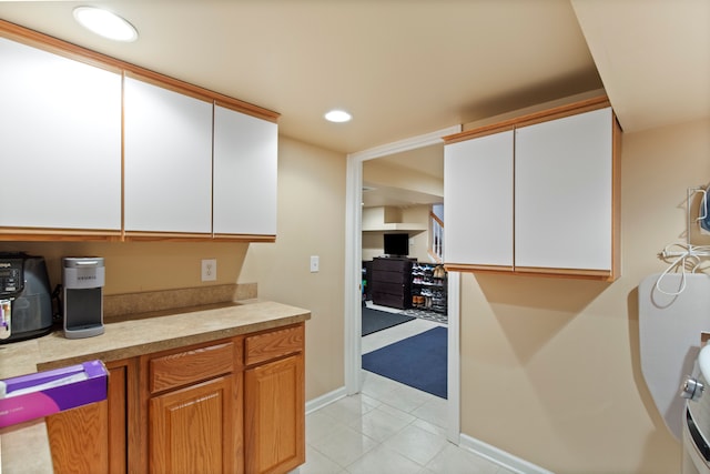 kitchen featuring light tile patterned floors, baseboards, white cabinets, light countertops, and recessed lighting