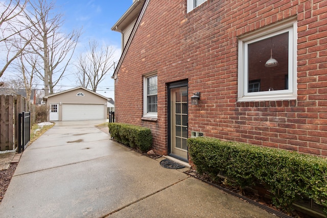 view of home's exterior featuring brick siding, a detached garage, fence, and an outdoor structure