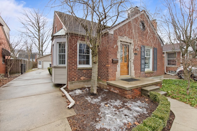 view of front of property with brick siding, a chimney, an outdoor structure, and fence