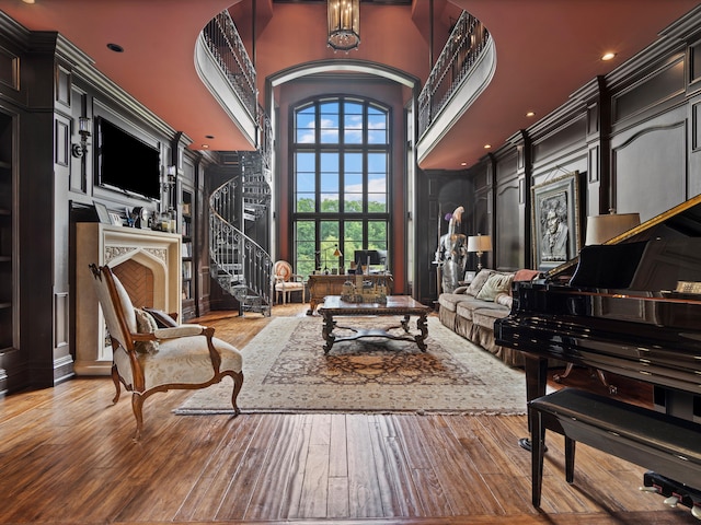 living area featuring stairs, wood-type flooring, and a towering ceiling