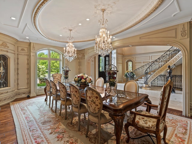 dining room featuring arched walkways, stairway, ornamental molding, a tray ceiling, and a chandelier