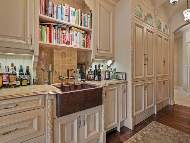 bar featuring arched walkways, indoor bar, tasteful backsplash, dark wood-type flooring, and a sink