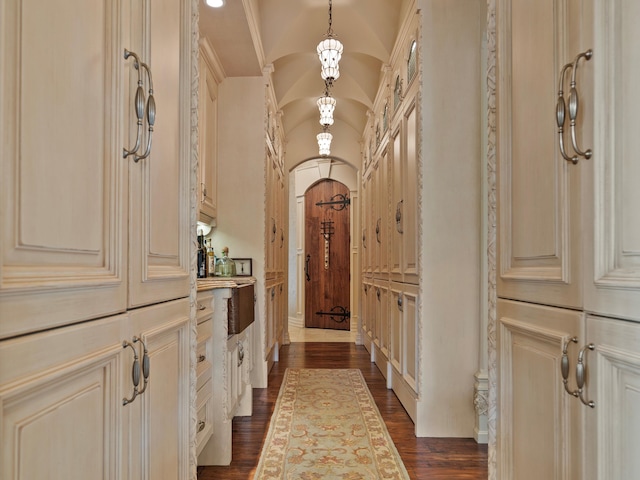 hallway featuring lofted ceiling, arched walkways, and dark wood finished floors