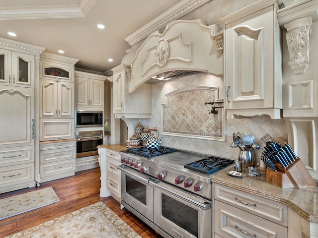 kitchen featuring tasteful backsplash, glass insert cabinets, appliances with stainless steel finishes, wood finished floors, and cream cabinets